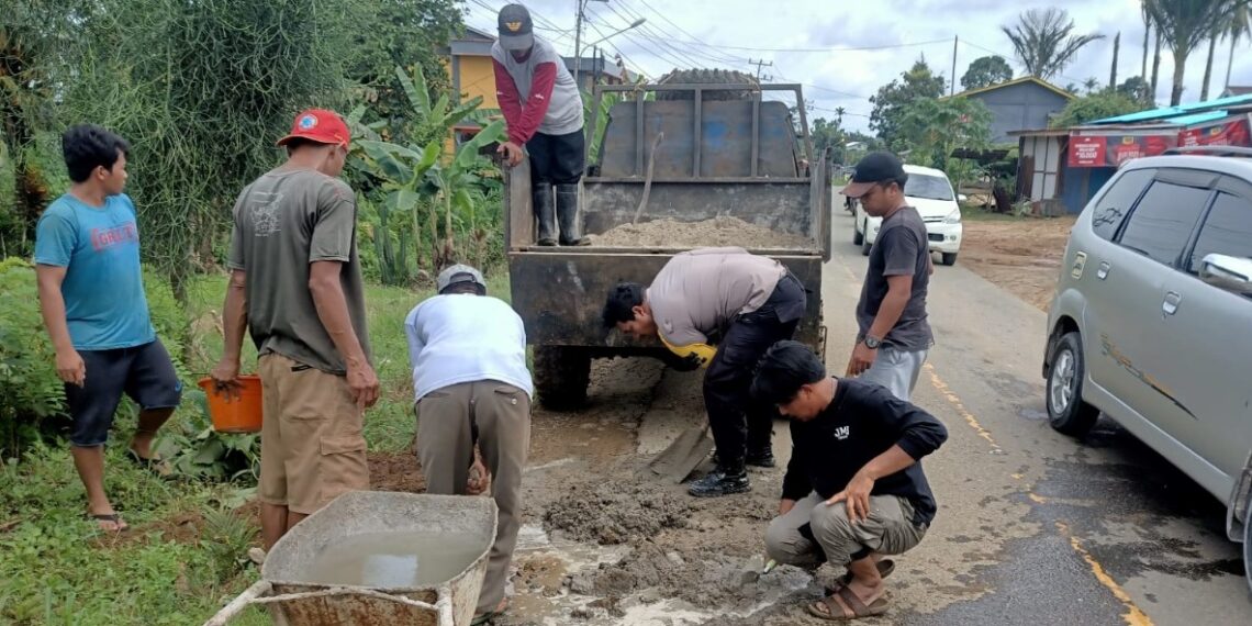 Polsek Sanggau Ledo Bersama Masyarakat Tambal Jalan Berlobang Digenangi Air Saat Hujan Kerap Terjadi Laka Lantas