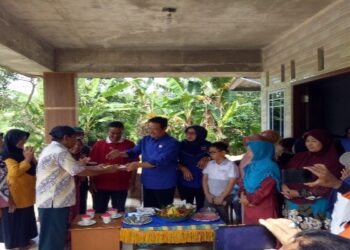 Wakil Ketua II DPRD Kota Tanjungpinang Hendra Jaya Saat Memberikan Potongn Tumpeng ke Salah Satu Warga. Foto Ist